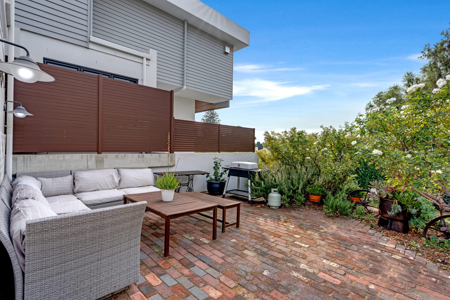 Brick courtyard with outdoor lounge and established planting